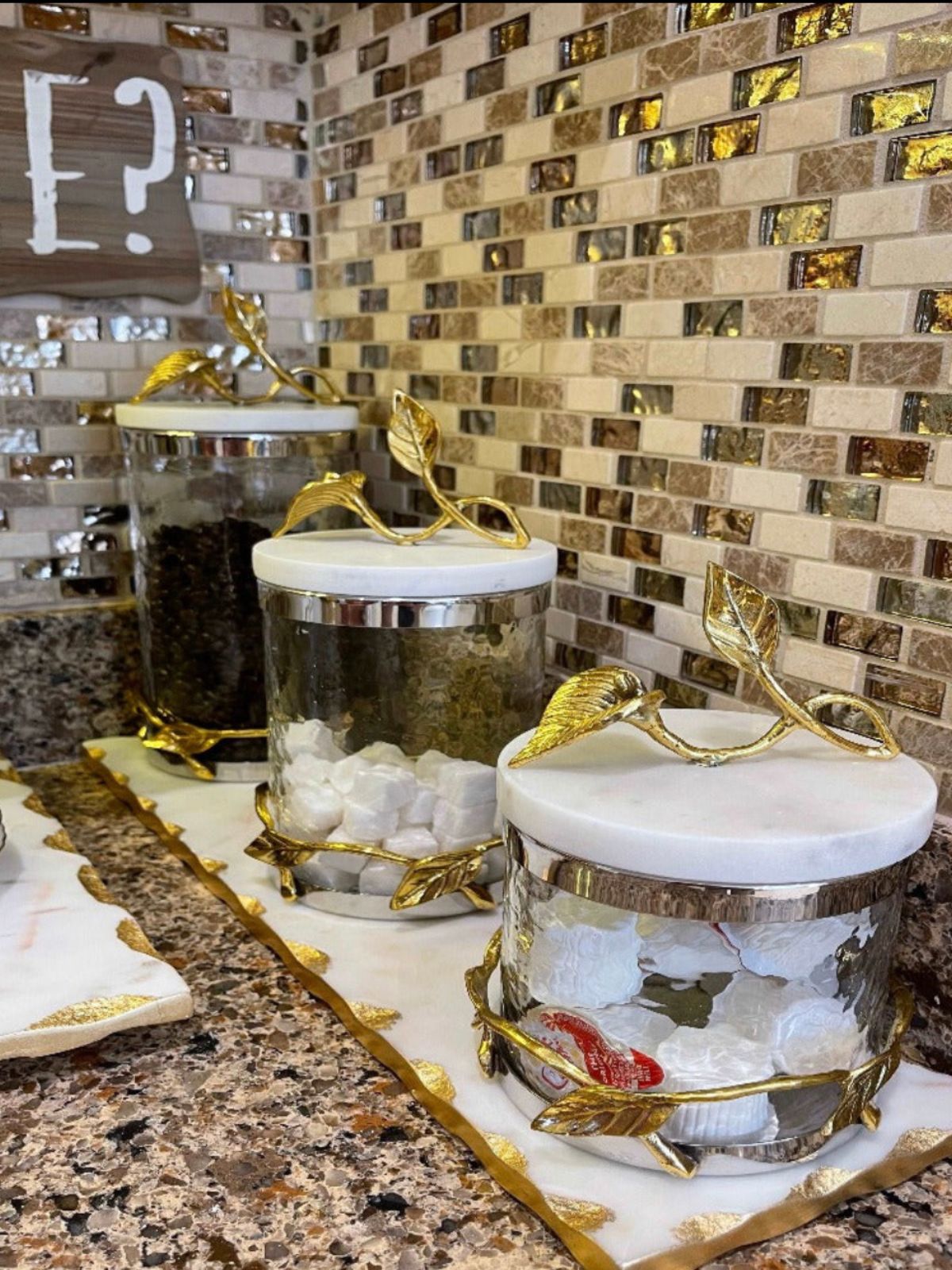 Beautify your counter with these hammered glass canisters and marble lid with the gold-tone dimensional leaf.