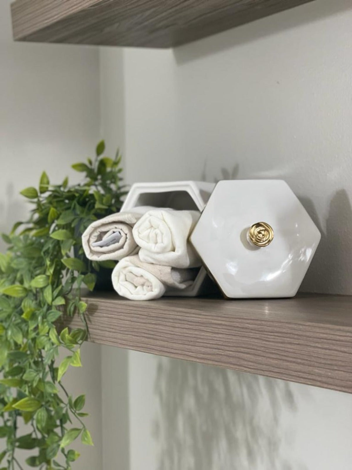 The Berkley White Hexagon Shaped Jar with Gold Flower Knob on Cover is perfect to place jewelry or condiments..